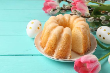 Lezzetli kek, Paskalya yumurtası, söğüt dalları ve açık mavi ahşap masada laleler, yakın plan.