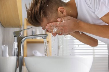 Tuvalette yüzünü yıkayan bir adam.