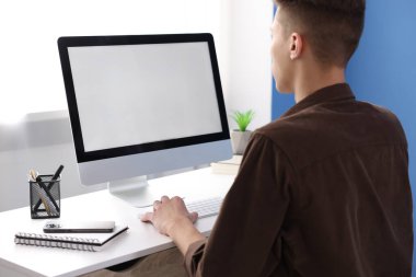 Ofisteki beyaz masada bilgisayarda çalışan bir adam. Tasarım için model