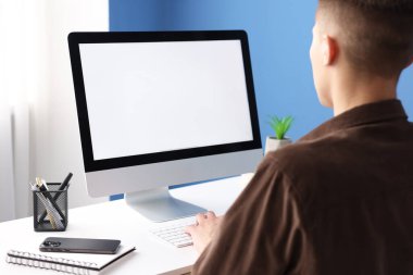 Ofisteki beyaz masada bilgisayarda çalışan bir adam. Tasarım için model