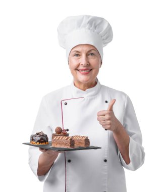 Tatlıları olan profesyonel pasta şefi beyaz arka planda başparmak gösteriyor.