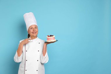Açık mavi arka planda pastası olan profesyonel pasta şefi. Metin için boşluk