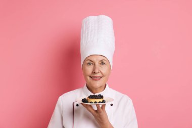 Profesyonel pasta şefi, pembe arka planda tatlı.
