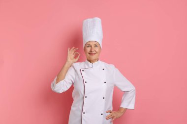 Profesyonel pasta şefi pembe arka planda iyi bir jest gösteriyor.