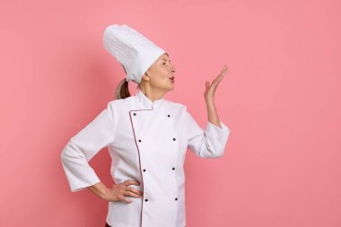 Profesyonel pastacı pembe arka planda şefin öpücüğünü yapıyor.