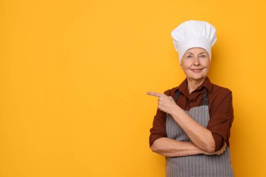 Turuncu arka plandaki bir şeyi işaret eden profesyonel bir şekerci. Metin için boşluk