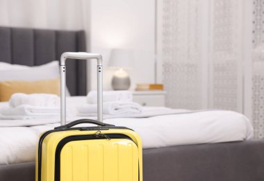 Otel odasında yatağın yanında şık bir bavul, yakın plan. Metin için boşluk