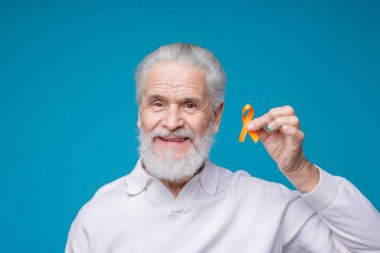 Çoklu Skleroz farkındalığı. Açık mavi arka planda turuncu kurdeleli son sınıf öğrencisi.