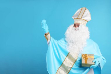 Açık mavi arka planda Noel hediyesi ile Aziz Nicholas, metin için boşluk