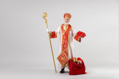 Açık gri arka planda hediyelerle dolu bir çuval ile Aziz Nicholas