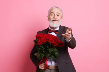 Pembe arka planda kırmızı gül buketi olan son sınıf öğrencisi.