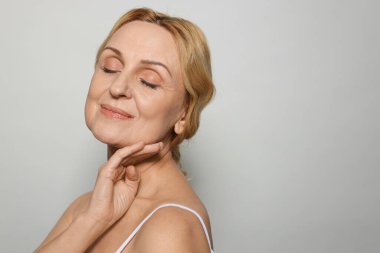 Gri arka planda orta yaşlı güzel bir kadın. Metin için boşluk