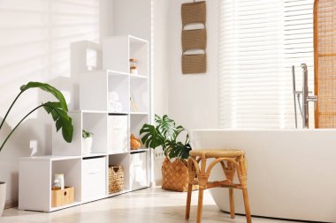 Rafları, küveti ve çiçekleri olan şık bir banyo.