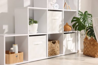 Farklı malzemeler ve ev bitkilerinin olduğu raf ünitesi.