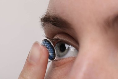 Açık arkaplana mavi renkli lens takan kadın, yakın plan
