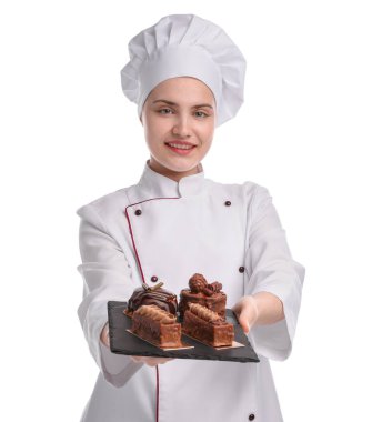 Üniformalı mutlu pastacı beyaz arka planda lezzetli çikolatalı tatlılar tutuyor.