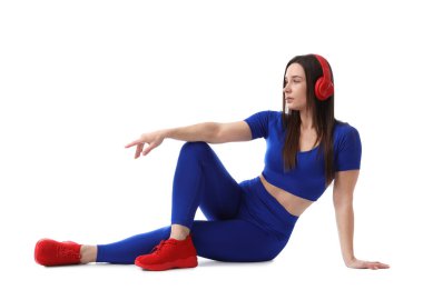 Beyaz arka planda duran kulaklıklı spor elbiseli kadın.