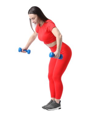 Spor kıyafetli bir kadın, beyaz arka planda halterlerle egzersiz yapıyor.