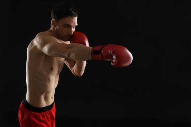 Siyah arka planda dövüşen boks eldivenli adam.
