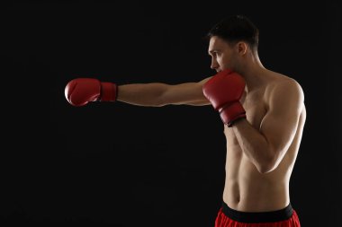 Siyah arka planda dövüşen boks eldivenli adam.