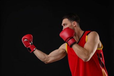 Siyah arka planda dövüşen boks eldivenli adam.