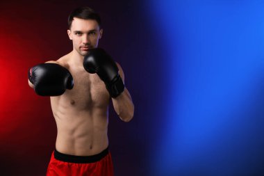 Boks eldivenli adam karanlık arka planda neon ışıklarda dövüşüyor, metin için yer var.