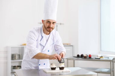 Şekerci çikolatayı mutfaktaki masada kekin üzerine rendeliyor, mesaj için yer var.