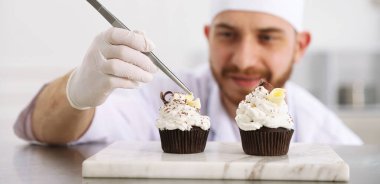 Şekerci, lezzetli kekler yapıyor. Mutfaktaki masada çikolata traşlı. Seçici bir odak noktası.