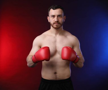 Siyah arka planda, neon ışıklarda boks eldivenli adam.