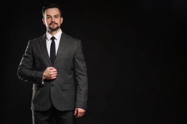 Siyah arka planda klasik takım elbiseli kendine güvenen bir adam. Metin için boşluk