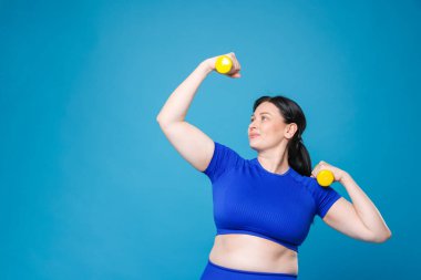 Ayrıca spor elbiseli bir kadın açık mavi arka planda dambıllarla egzersiz yapıyor, mesaj için yer var.