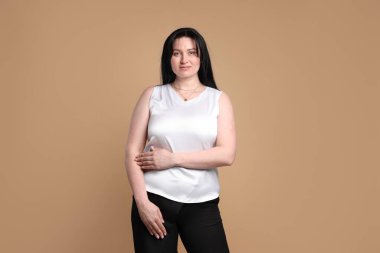 Bej arka planda çekici ve büyük beden modelinin portresi. Fazla kilolu