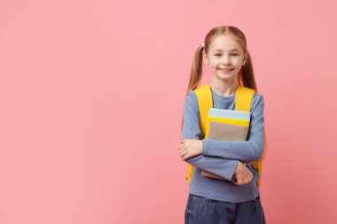 Sırt çantası ve pembe arka plan kitapları olan liseli kız. Metin için boşluk