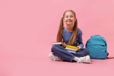 Sırt çantası ve pembe arka plan kitapları olan liseli kız. Metin için boşluk