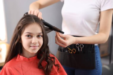 Güzel kız kuaförde saç buklesi yaptırıyor.