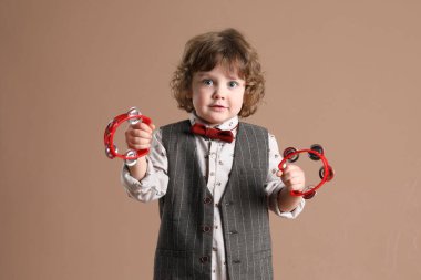 Kahverengi arka planda oyuncak tef çalan sevimli küçük çocuk.