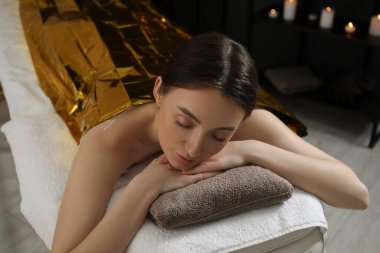 Vücuduna termal folyo örten kadın spa salonunda tedavi görüyor.