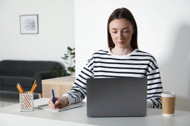 İçerideki masada ders sırasında not alan bir kadın. Kendi kendine çalışma.