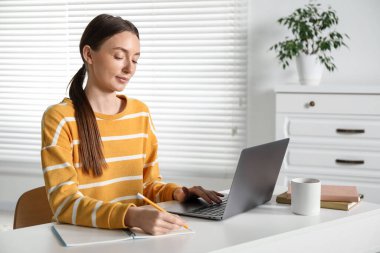 İçerideki masada ders sırasında not alan bir kadın. Kendi kendine çalışma.