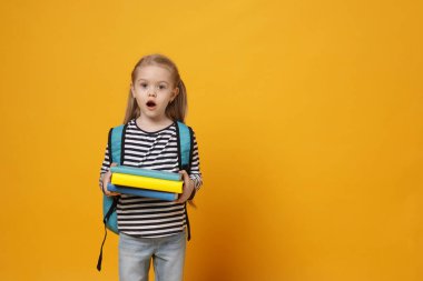 Sırt çantası ve sarı arka plan kitapları olan sürpriz bir kız öğrenci. Metin için boşluk