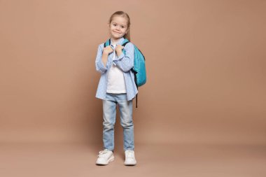Kahverengi arka planda sırt çantası olan tatlı bir kız öğrenci.
