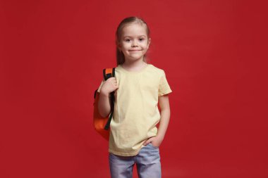 Kırmızı arka planda sırt çantası olan tatlı bir kız öğrenci.