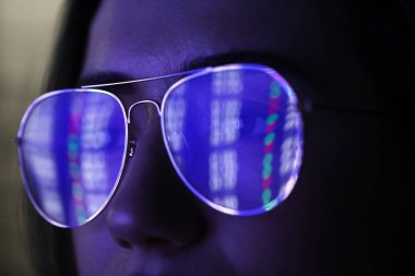 Siyah arka planda yansıması olan gözlüklü genç bir kadın, yakın plan.