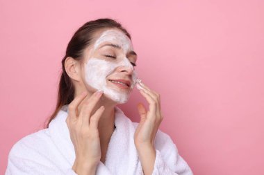 Spa günü. Yüzüne pembe arka planda maske takan güzel bir kadın. Mesaj için boşluk.