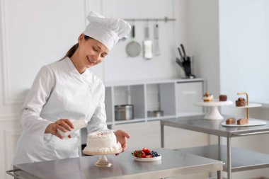 Bir şişe soslu şekerlemeci mutfakta pasta yapıyor.