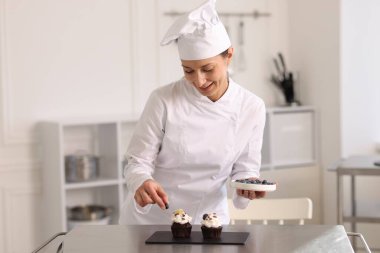 Şekerci mutfakta yabanmersinli kek dekore ediyor.