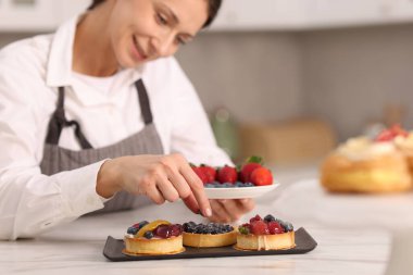 Sofrada yaban mersinli tart dekorasyonu yapan şekerci, seçici odak