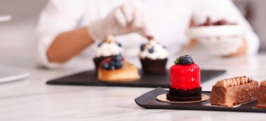 Şekerci, kek süsleme masasında bir parça çikolatayla, seçici odaklı.