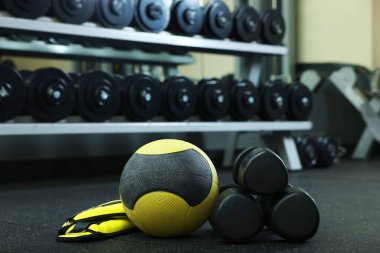 Sarı ilaç topu, ayak bileği ağırlığı ve spor salonunda yerde dambıllar.