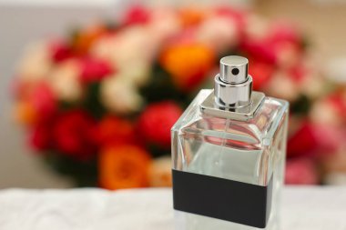 Güzel güllere karşı bir şişe parfüm, yakın plan. Metin için boşluk